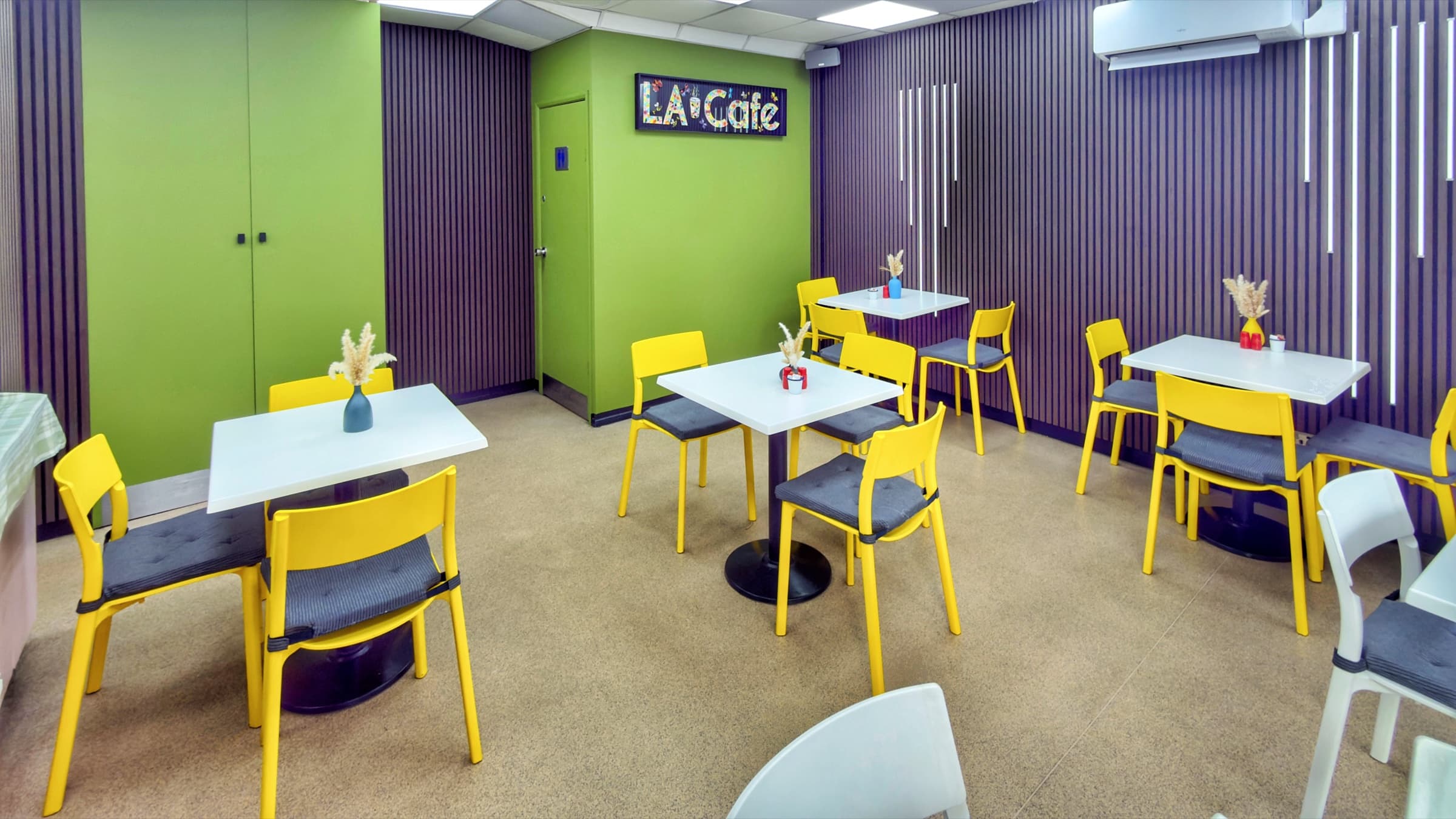 LA Cafe Bistro interior — green accent wall with illuminated LA Cafe sign